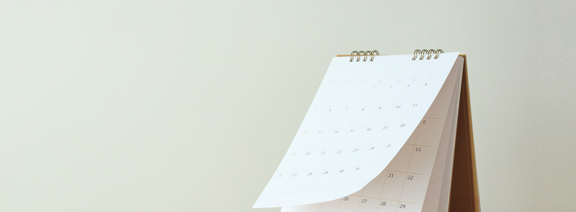 The image features a wall calendar with a spiral binding, displayed against a plain background.