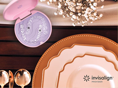 The image shows a table setting with a purple cosmetic case, a plate, and other items, along with a sign for Invisalign dental services.