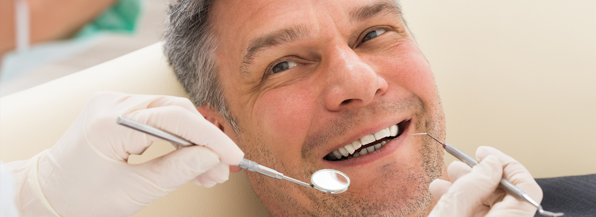 A person in a dental chair receiving dental treatment, with visible dental tools and a smiling expression.