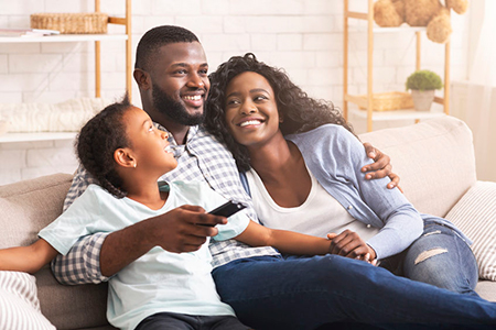 A family of four sitting together on a couch, smiling and enjoying each other s company.