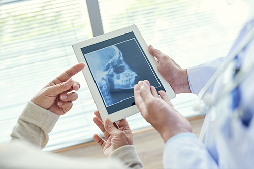 A medical professional uses a tablet to show an X-ray to a patient in a modern healthcare setting.