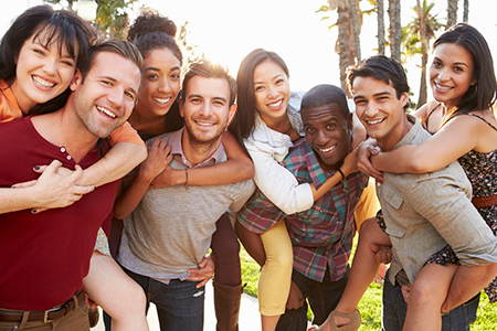The image shows a group of young adults posing together outdoors during the daytime with smiles on their faces.