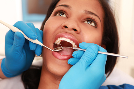 A woman receiving dental treatment with a dentist performing oral surgery.